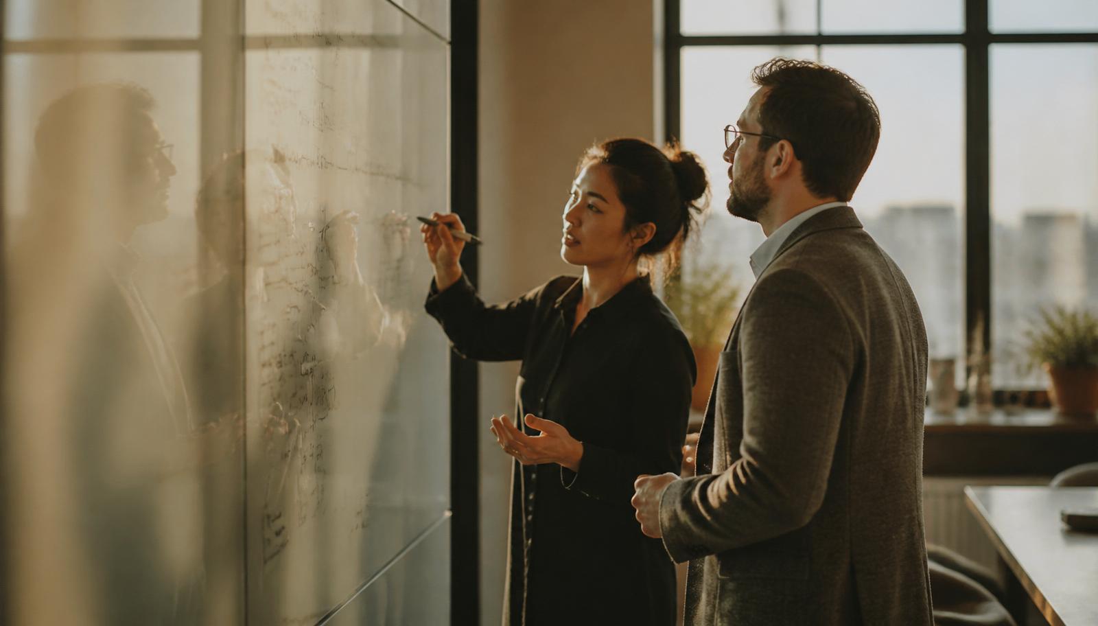 Colleagues at a whiteboard mid-conversation
